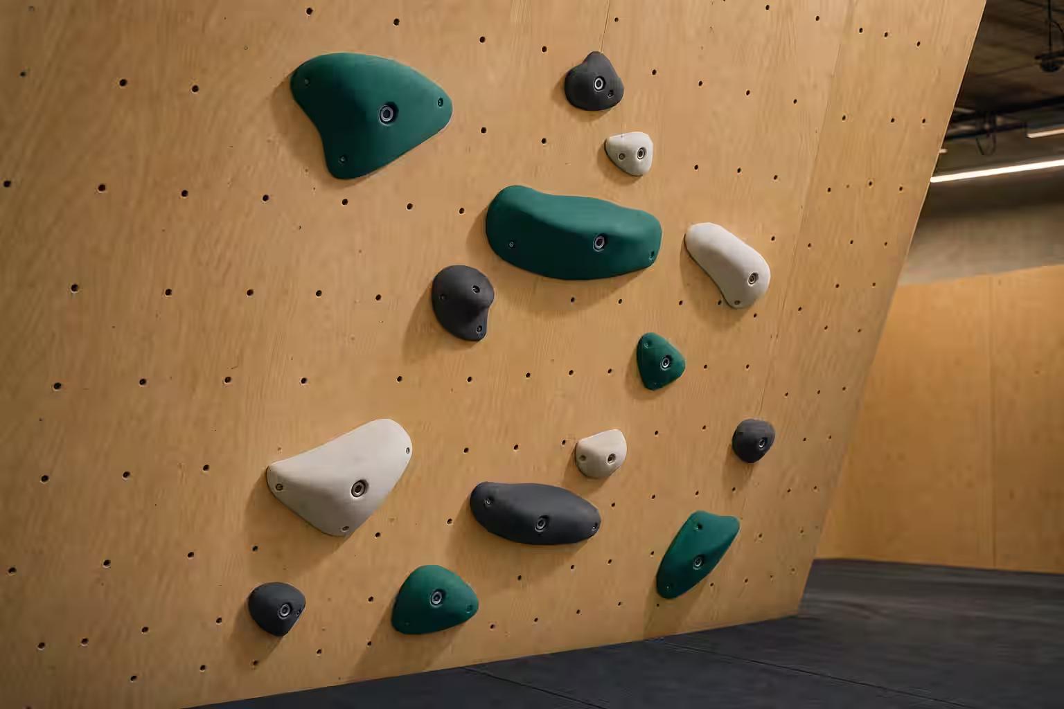 Presas de escalada de material compuesto con superficies texturizadas y fijaciones visibles en un muro contemporáneo.
