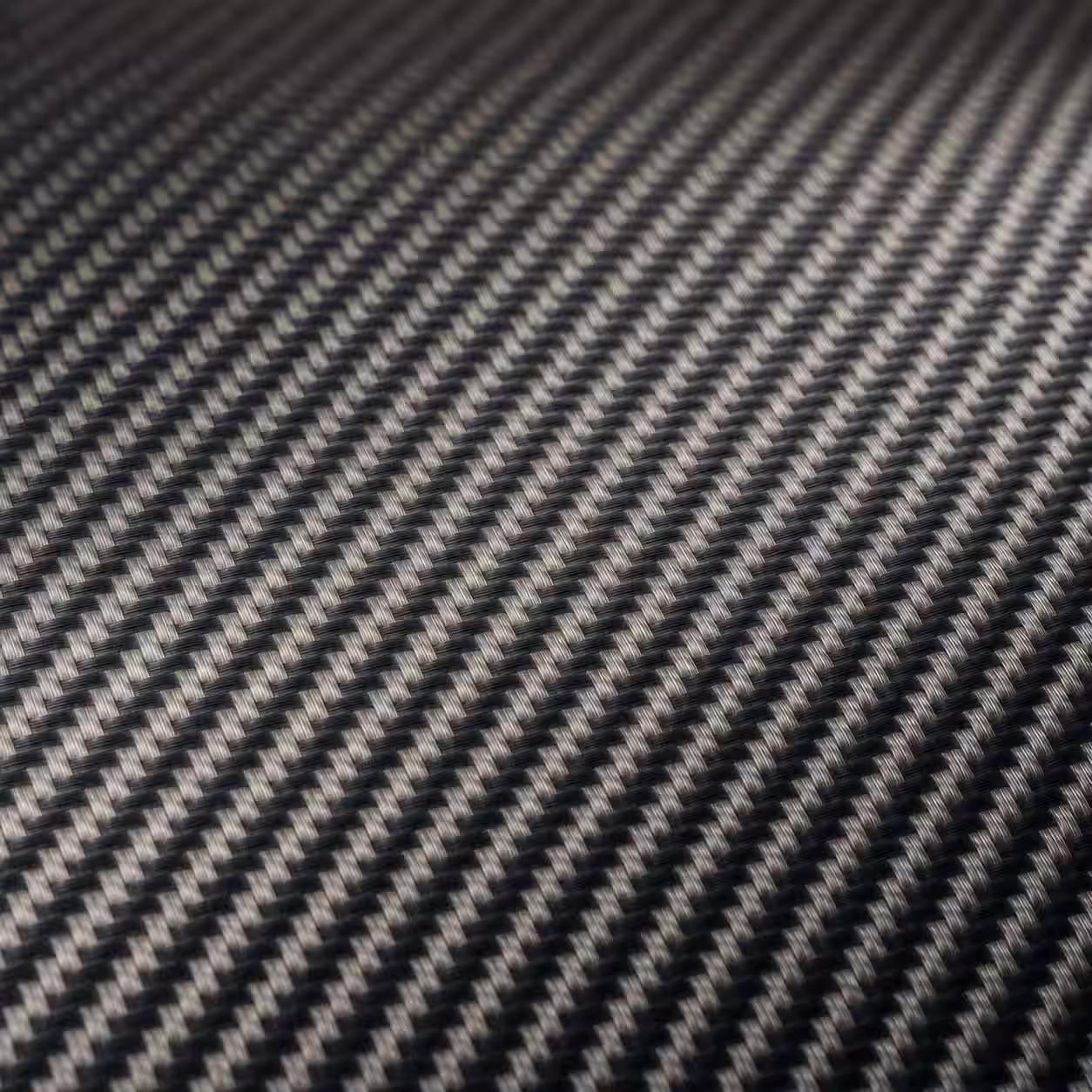 Tejido de fibra de carbono impregnado con resina visto en macro, con trama continua y reflejo controlado.