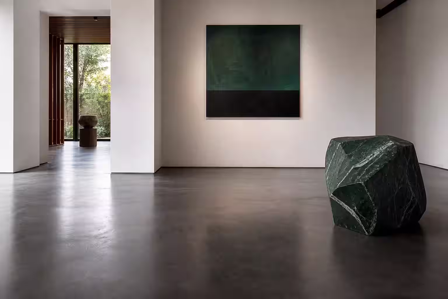Piso epoxi grafito de reflejo moderado en una galería contemporánea con muros blancos cálidos.