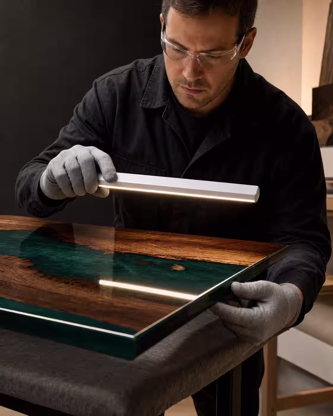 Persona con guantes limpios inspecciona el borde y el reflejo de una pieza terminada bajo luz rasante.