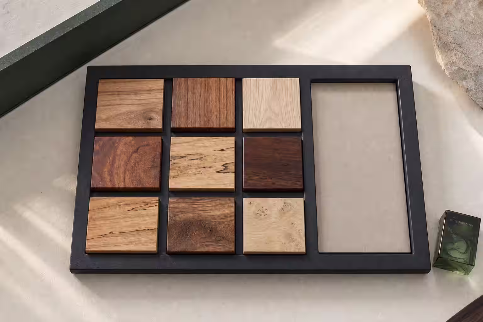 Vista cenital de nueve muestras de madera en distintos tonos, un espacio para material del cliente y una muestra circular de resina verde.